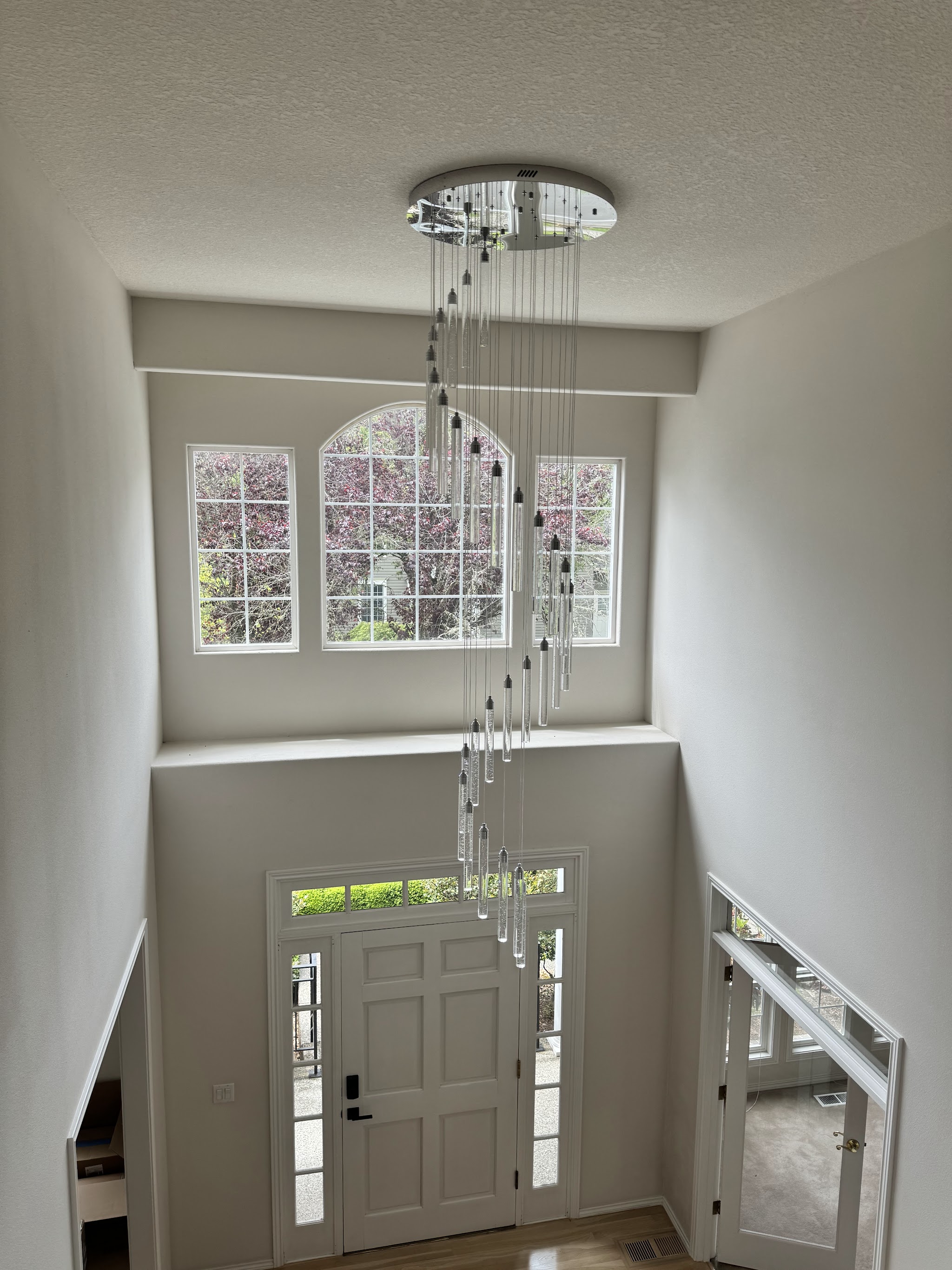 Completed cascading multi-pendant chandelier installation in a two-story foyer